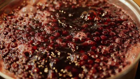Rich crimson dye bubbles as cranberries boil with onion skins in rustic kitchen