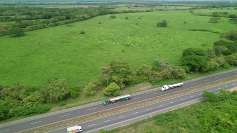 aerial: flying above two freight trucks transporting oil along the highway.