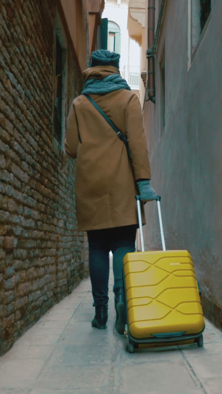 Woman with Yellow Suitcase Walking in Alley