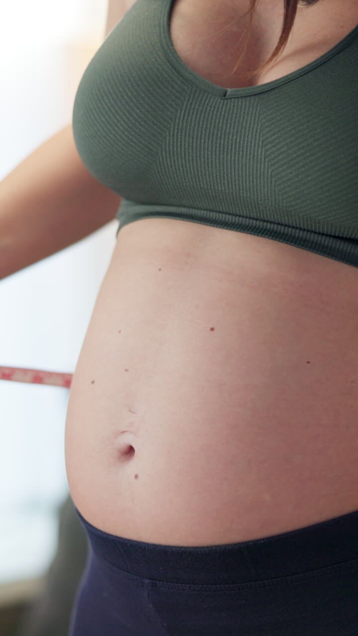 Pregnant Woman Measuring Her Belly with a Tape Measure