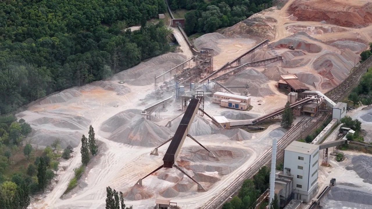 An extensive quarry operation with heavy machinery processing raw materials under an aerial view.