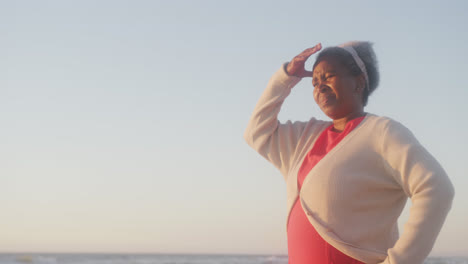 Happy-senior-african-american-woman-walking-at-beach,-in-slow-motion,-with-copy-space