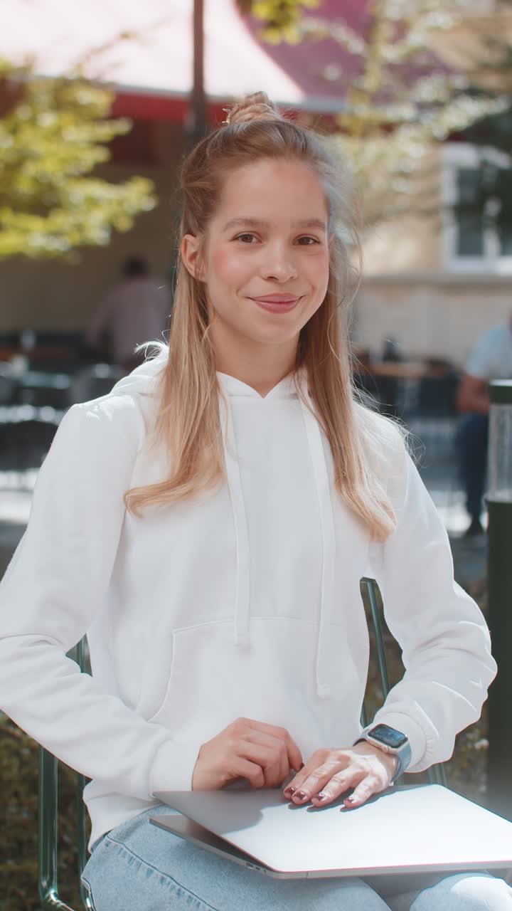 Happy young woman freelancer sitting in city street closes laptop screen finishing working online