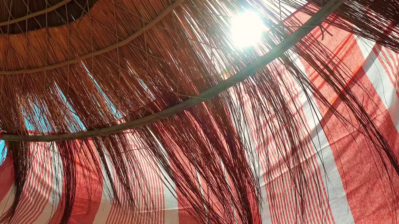 la luz del sol se muestra a través del techo de paja de una cabaña en la playa -slowmo fpv