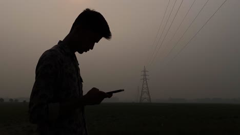 a young south asian boy is using a smartphone in the evening