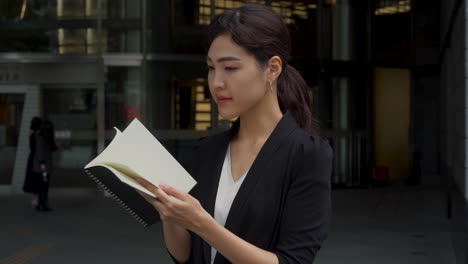 Japanese-business-woman-reads-notebook.-Asian-female-worker.-Medium-shot.