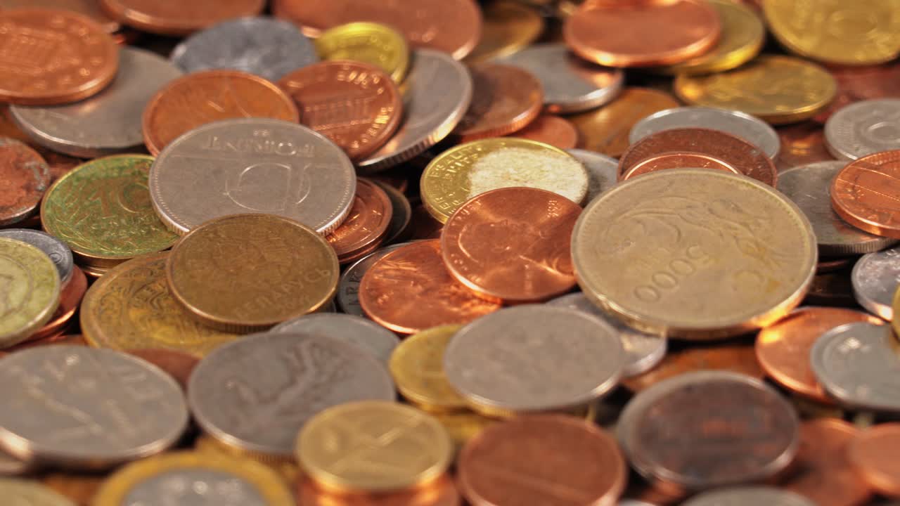 Variety of coins scattered on a surface in natural light during daytime
