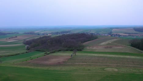 Flying-above-rural-landscape-with-hills-and-cultivated-fields-in-agriculture-environment