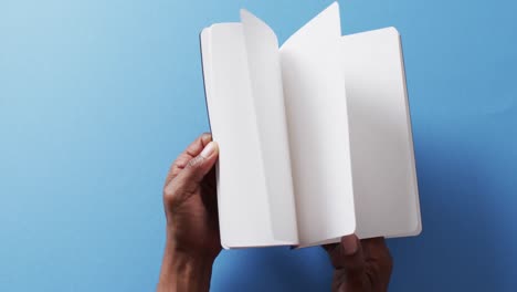 close up de la mano hojeando un libro con espacio de copia en fondo azul en cámara lenta