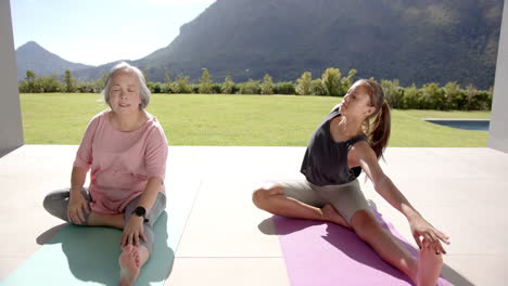 stretching on yoga mats, asian grandmother and granddaughter exercising together outdoors