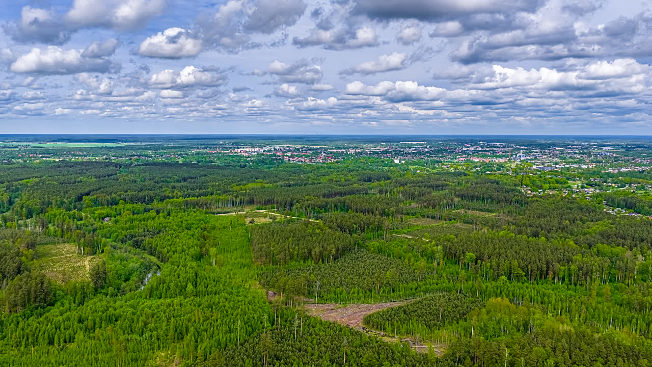 Dense Thicket Overlooking Rural Town Under Cloudscape. Time Lapse