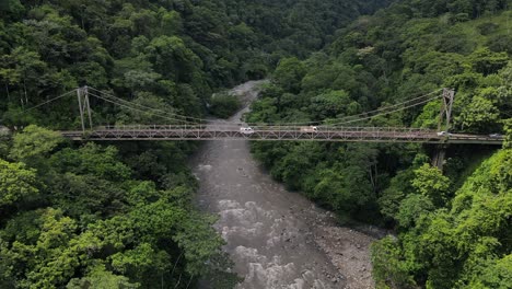 Trucks-and-vans-crossing-old-run-down-steel-bridge-in-the-jungle-of-south-America