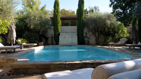 Exterior-view-of-outdoor-pool-with-sunbeds-in-garden-of-a-luxurious-modern-castle-in-southern-France