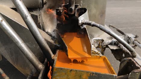 primer plano de pintura termoplástica naranja caliente goteando en una máquina de marcador de líneas