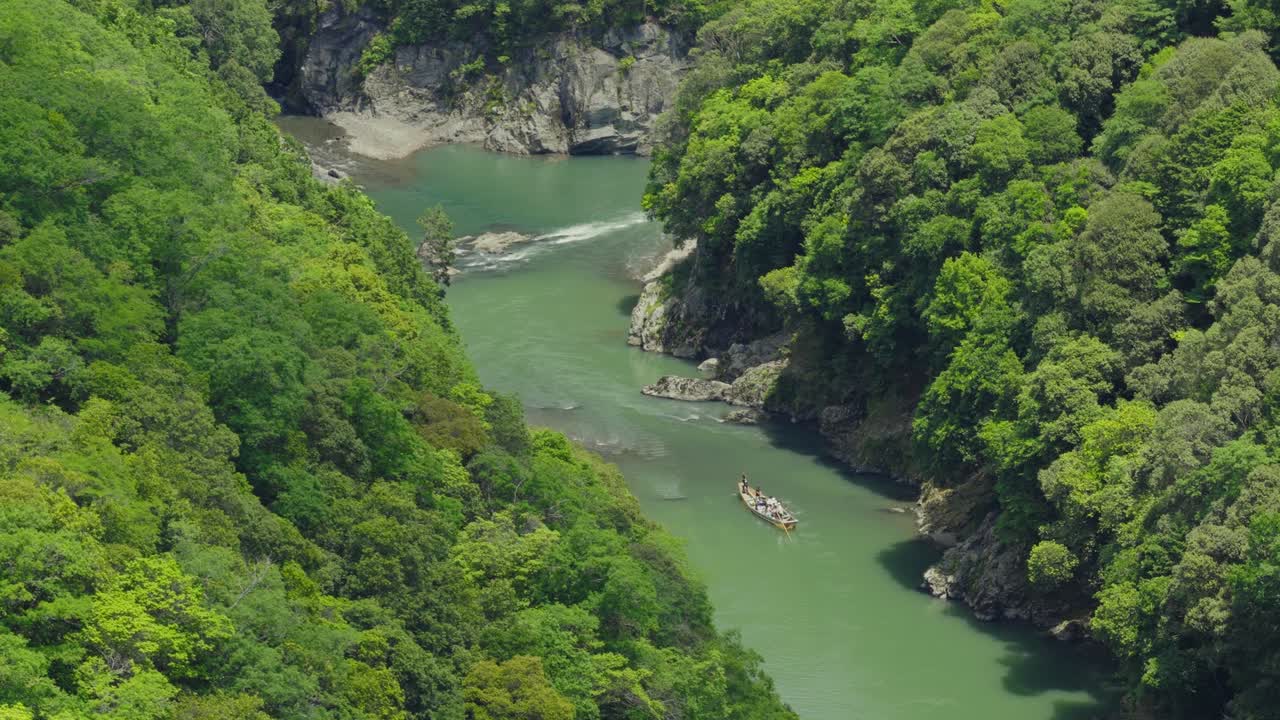Aerial follows traditional Japanese boat sailing in Hozugawa River, romantic Ride, Travel Spot of Kyoto Japan