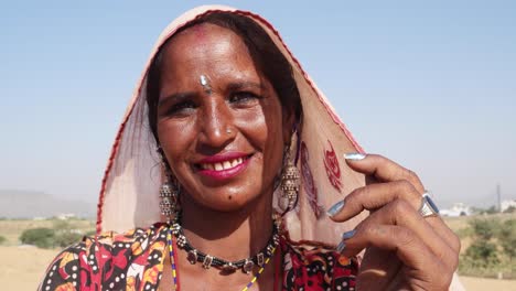 close portrait of a smiling nomad woman covering her face with her scarf