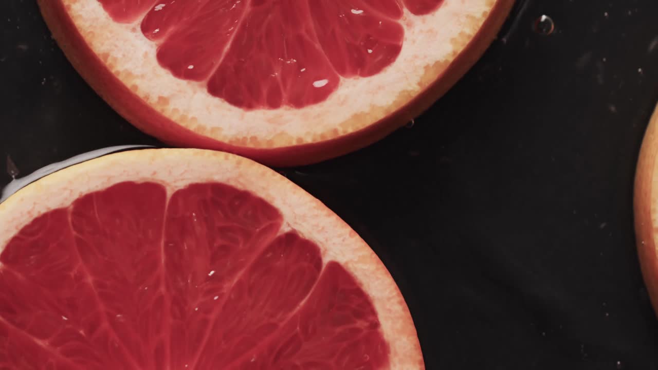 micro video de primer plano de rebanadas de pomelo rojo con espacio de copia en fondo negro