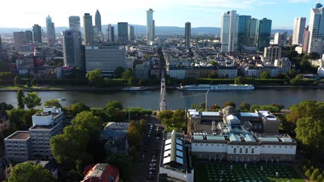 el centro de frankfurt, alemania, por encima del puente colgante mientras los barcos y los transbordadores cruzan por debajo.