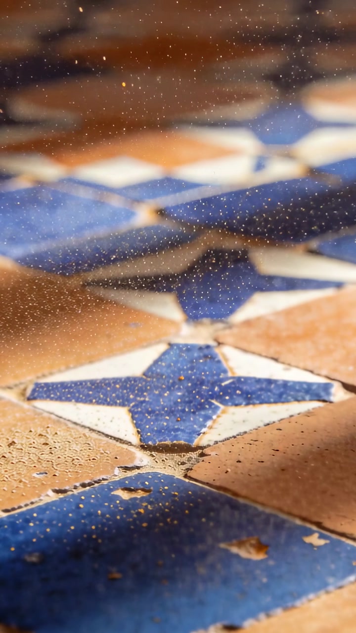 Vertical video: Camera pulling focus to worn glazed tile on floor, dust motes revealing chips