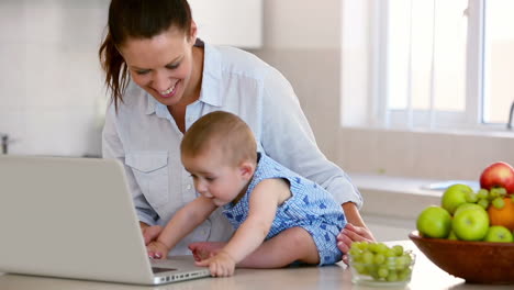 Pretty-mother-using-laptop-and-playing-with-baby