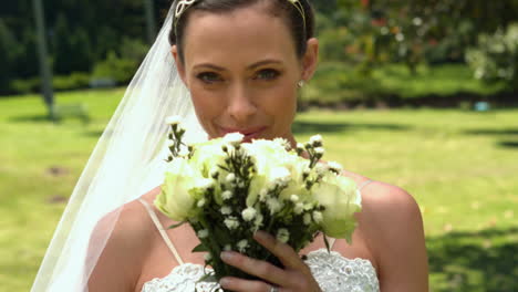 bride smelling her bouquet in the park