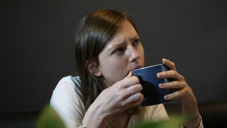 una joven pensativa bebiendo café de una taza profundamente pensando en un problema