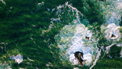 aerial birds eye over dark green waves of pacific ocean approaching coastline of chiloe island