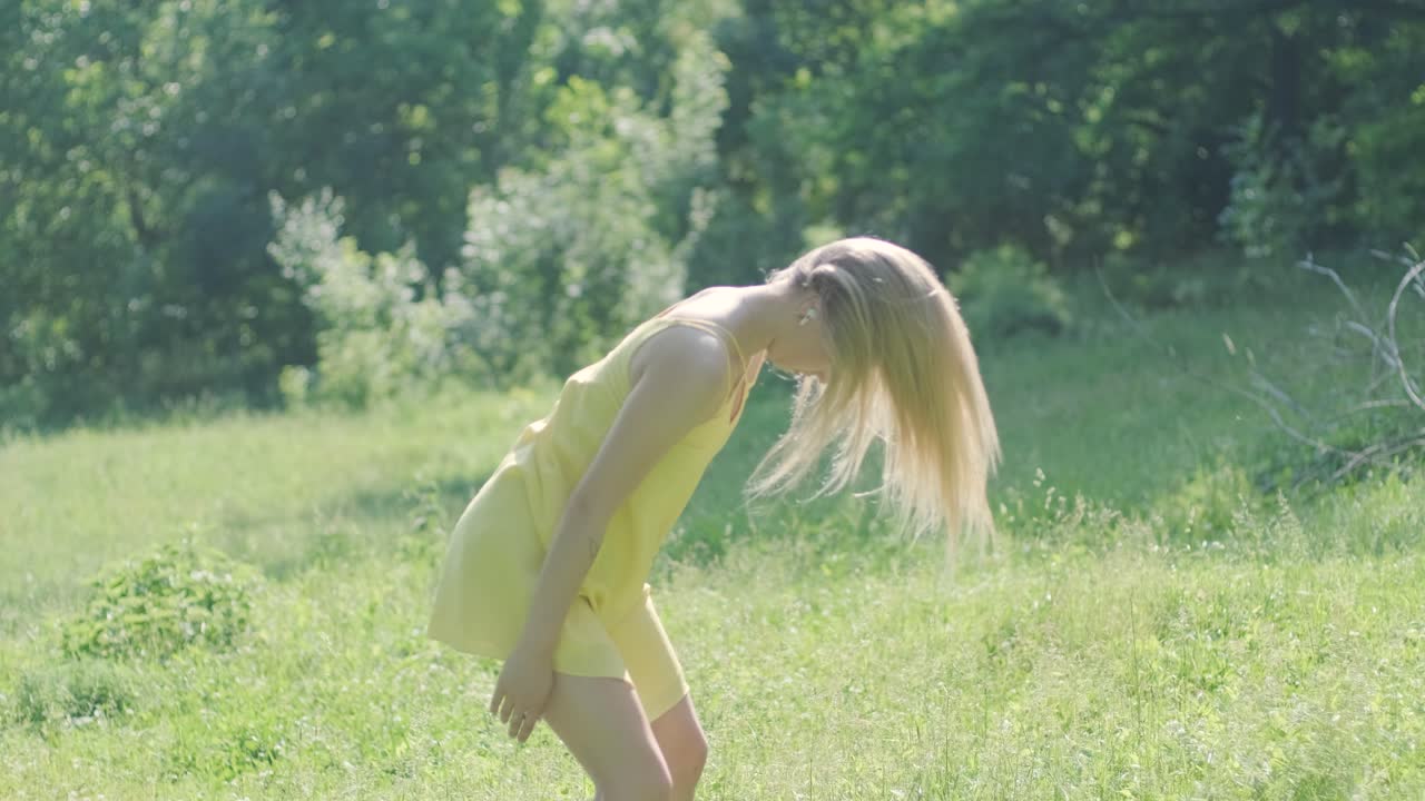 노란색 드레스를 입은 여자가 여름 공원에서 우아하게 춤을 춘다