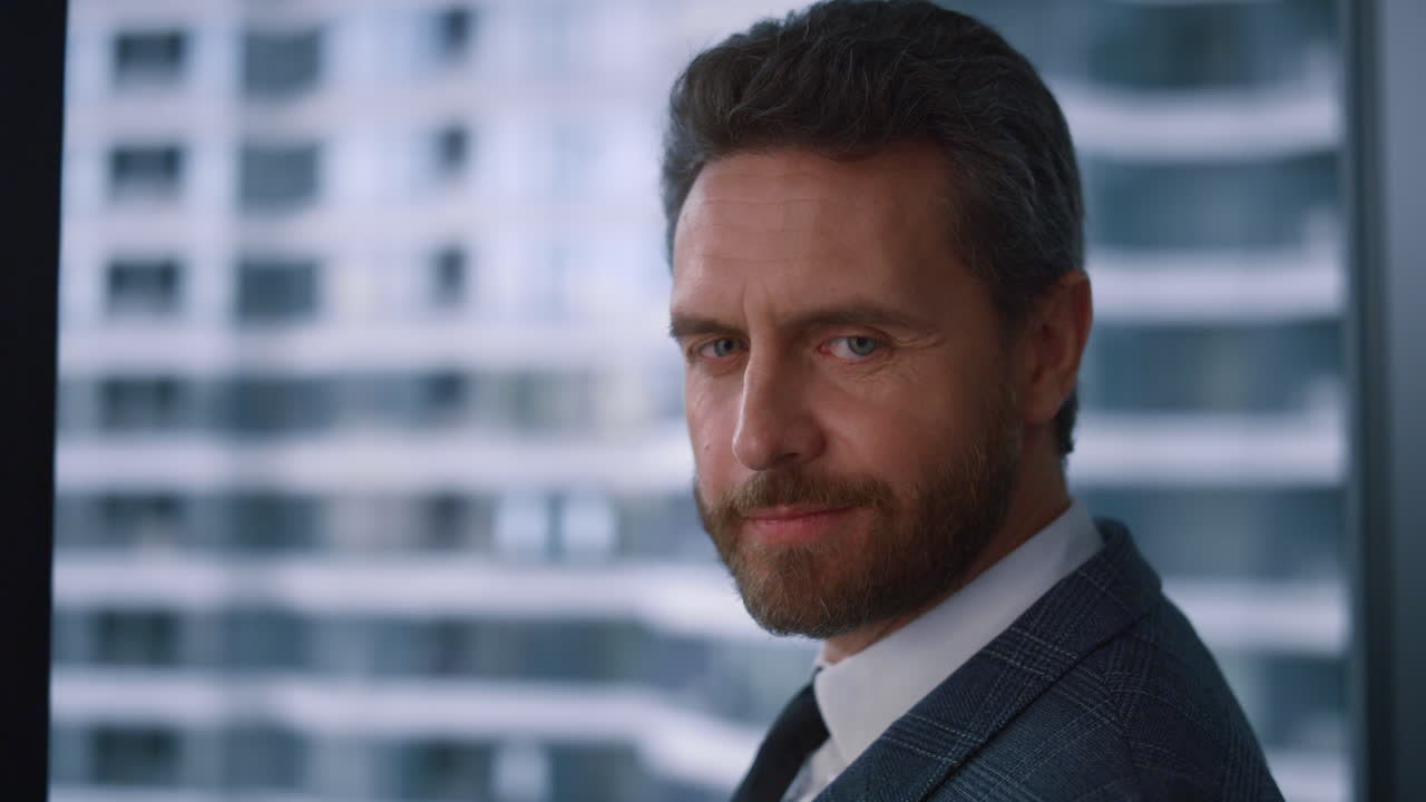 hombre corporativo confiado posando girando la cabeza mirando la cámara en la oficina de la compañía.