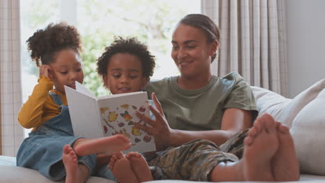 Madre-Del-Ejército-En-Uniforme-En-Casa-De-Licencia-Con-Niños-Leyendo-Un-Libro-Juntos-En-El-Sofá