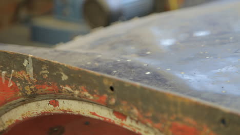 Old-Red-Rusty-Car-Chassis-in-Garage-Dolly-Shot-with-Shallow-Depth-of-Field