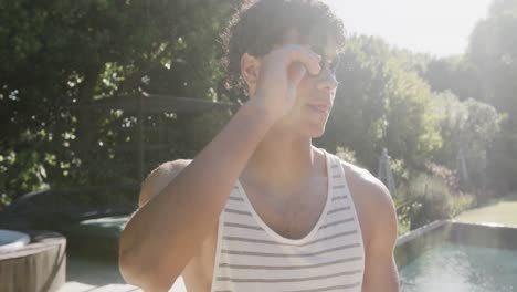retrato de un feliz hombre biracial con gafas en el jardín en un día soleado