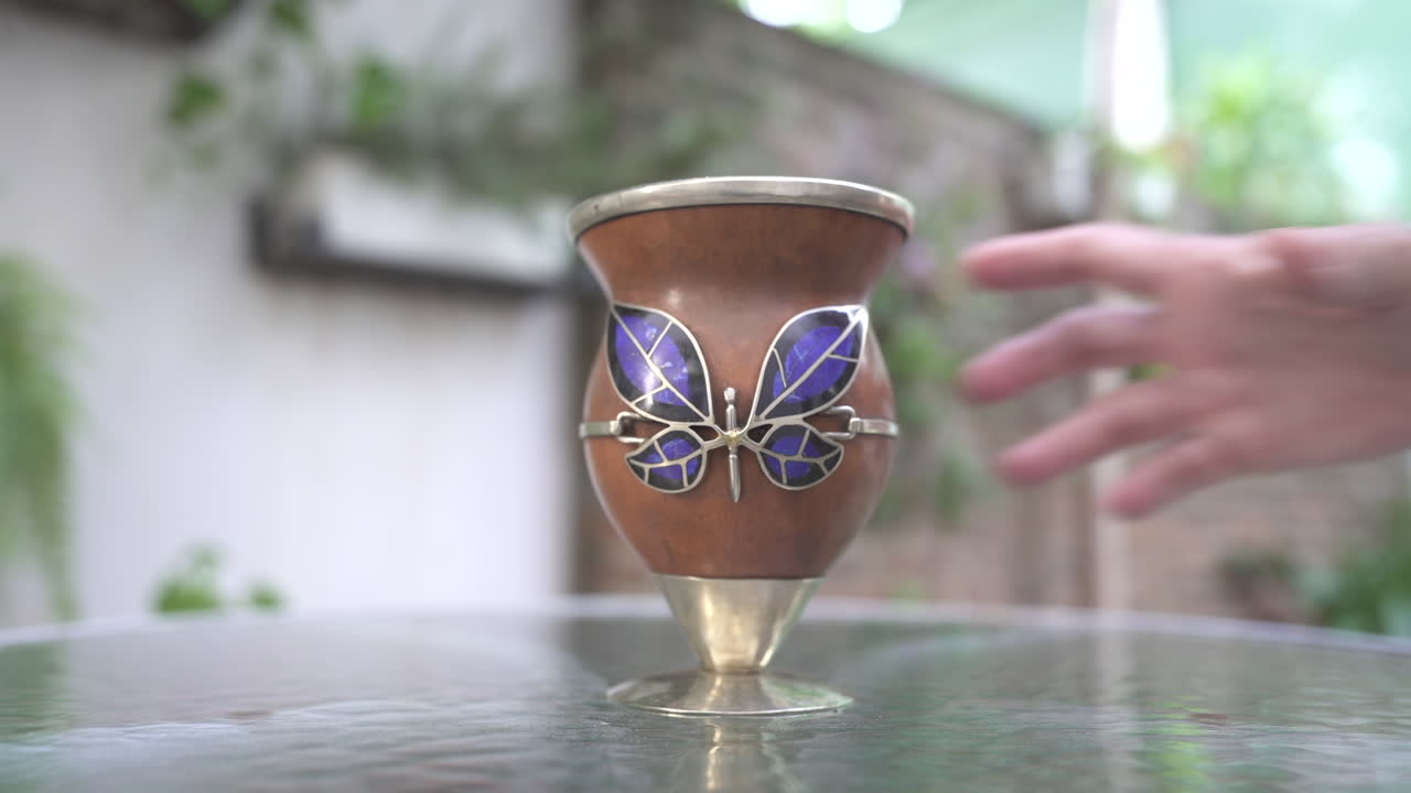 una mano recogiendo una calabaza mate y devolviéndola a su posición original