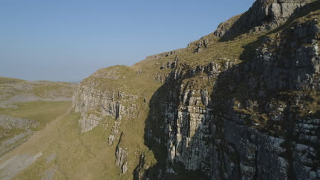 primer plano aéreo drone tiro volando más allá de warrendale nudos acantilados yorkshire dales hermoso campo hierba y colinas rocosas en un día soleado de verano reino unido con pájaros volando