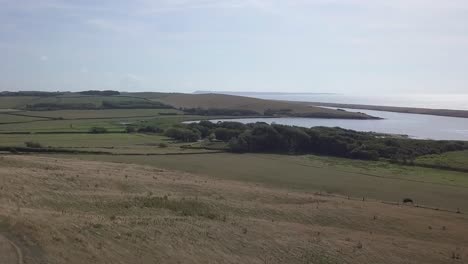 low forward tracking aerial down a hill towards the fleet lagoon at the west end of chesil beach