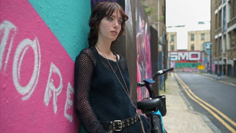 close up outdoor fashion portrait of young alternative style woman leaning against graffiti covered wall in london city street uk in real time 4