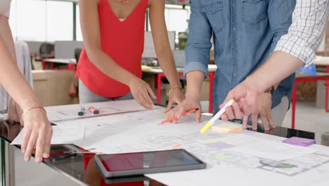 mid section of team of diverse architects discussing over a plan at office