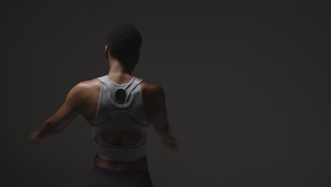 studio shot of young woman wearing gym fitness clothing warming up for exercise 2