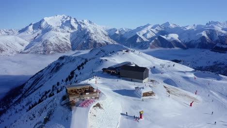 aerial rotation focusing on ski resort on top of snow capped mountain on a sunny day