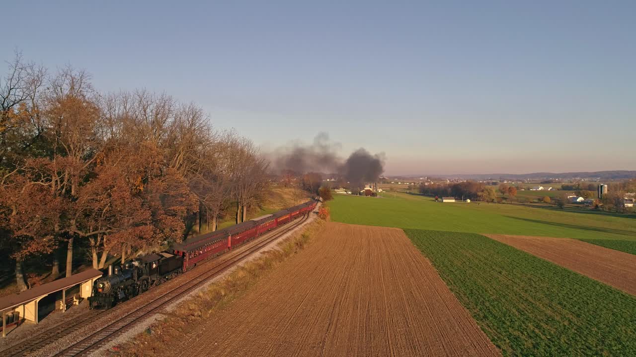 늦은 오후 황금시간대에 객차를 끌고 연기와 증기를 내뿜는 골동품 증기 기관차의 공중 전망