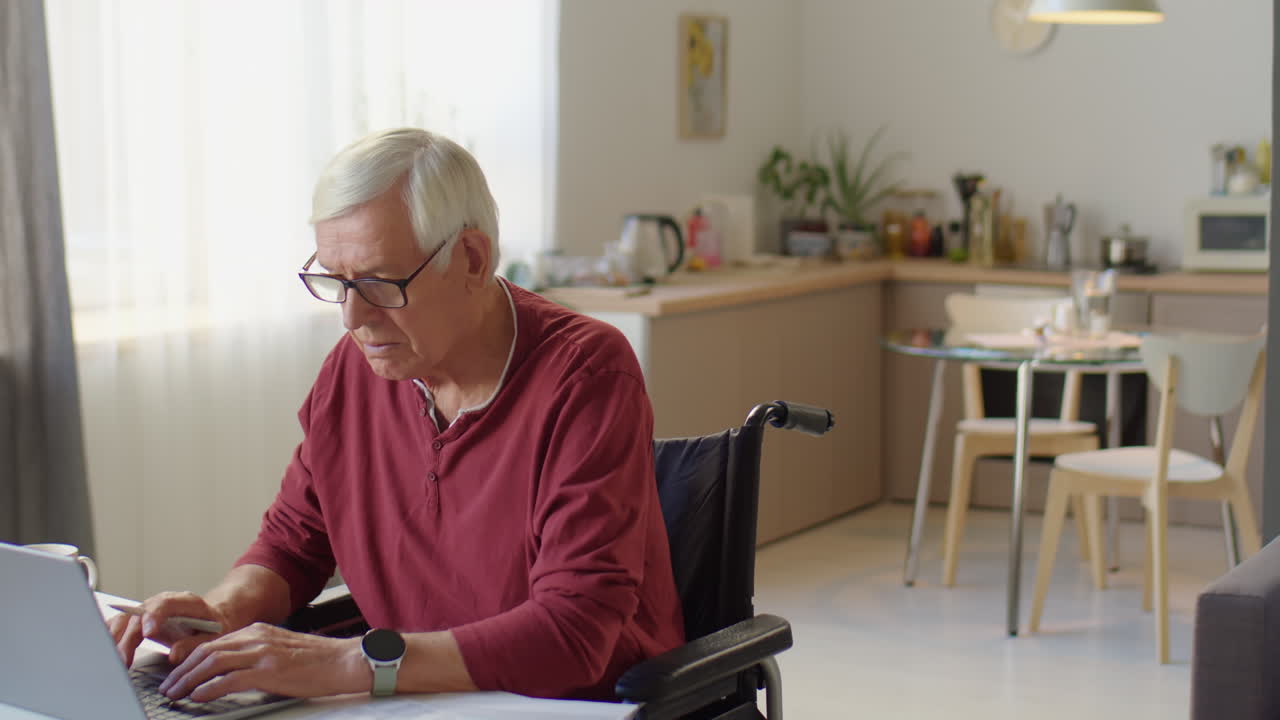Senior Businessman in Wheelchair Working at Home
