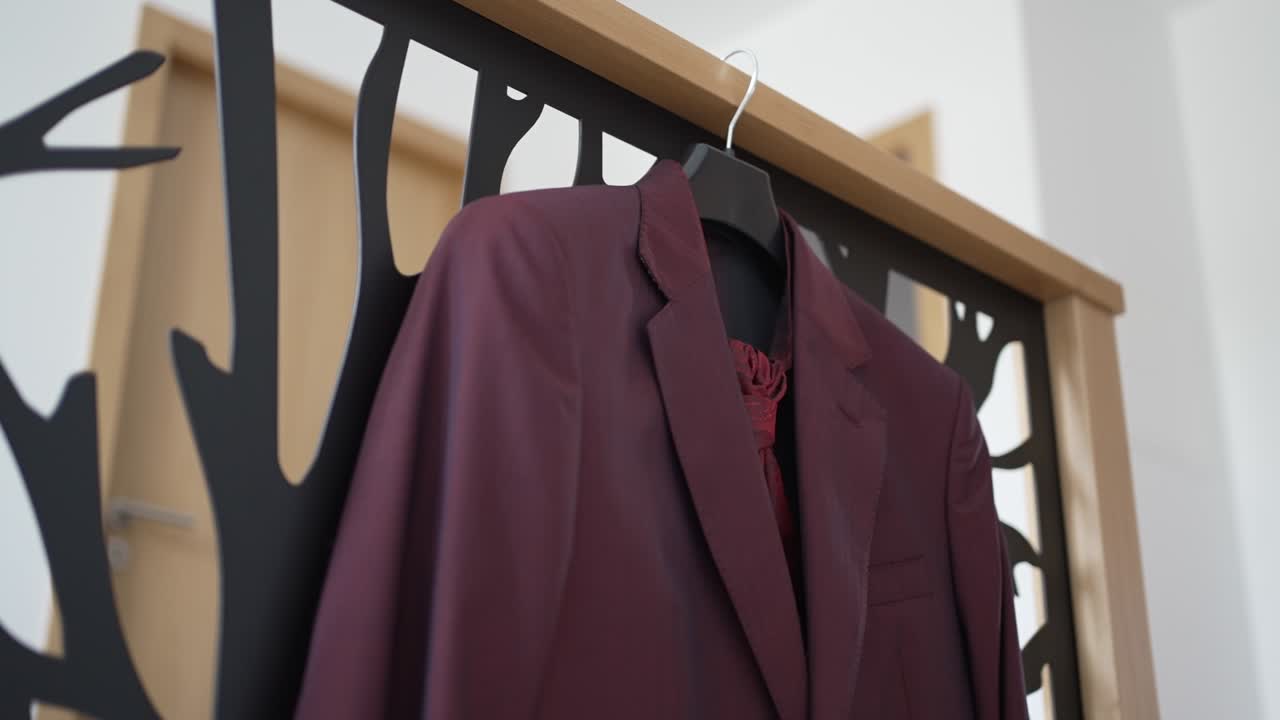 Burgundy suit jacket displayed on modern black and wood hanger for wedding