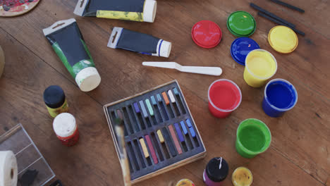 close up of paints and brushes on table in studio, slow motion