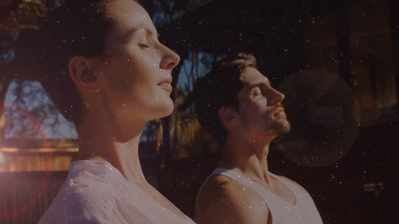Animation of light spots over caucasian couple practicing yoga and meditating