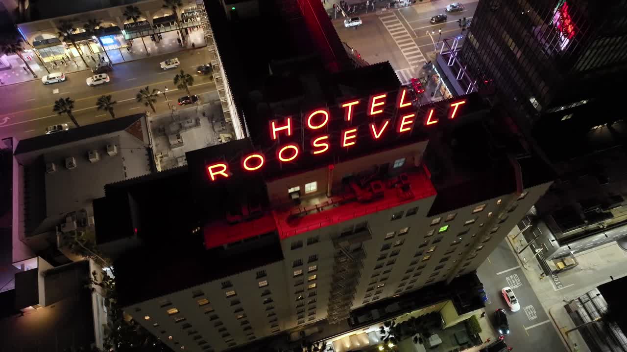 Establishing view of famous The Hollywood Roosevelt Hotel, aerial flyover at night looking down onto the streets in Los Angeles