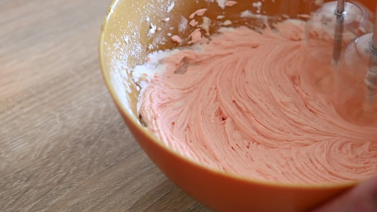 Electric Mixer Blending Pink Frosting in a Bowl