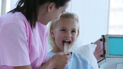 nurse checking a little girls throat in hospital