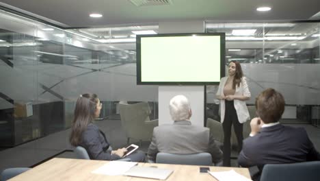 Focused-female-speaker-talking-while-standing-near-display