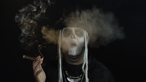 creepy man with skeleton makeup in top-hat. guy smoking cigar, opening his eyes, making faces