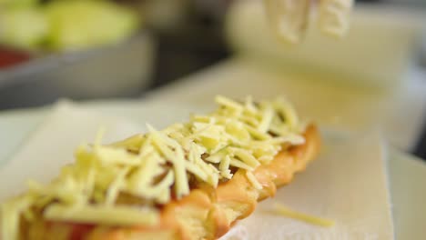 colocando queso con guantes encima de un perrito caliente